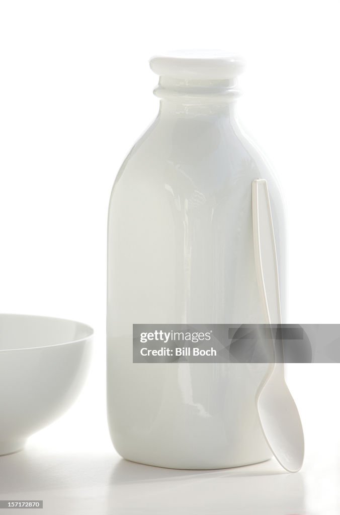 White milk bottle, bowl and spoon on white