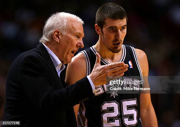 Nando de Colo of the San Antonio Spurs talks with head coach Greg Popovich during a game against the Miami Heat at American Airlines Arena on...