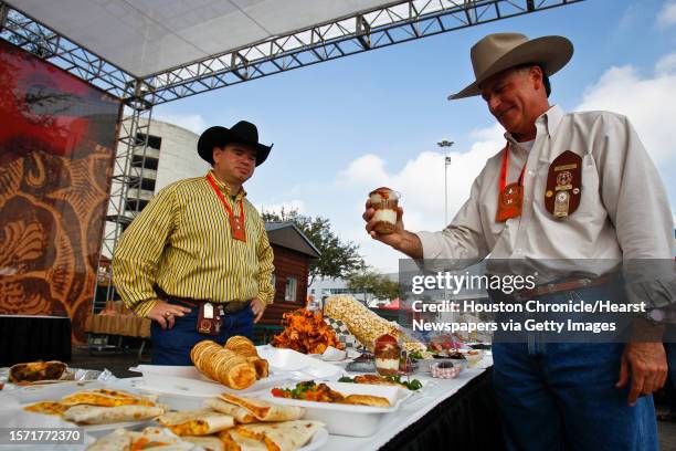 Rick Harsch holds Bum's Blue Ribbon Pulled Pork Sundae as Jay Justilian looks on while organizing entered food during the 3rd Annual Gold Buckle...