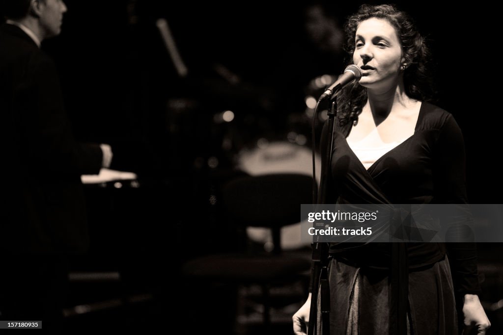 Bigband: female jazz singer in performance behind the microphone