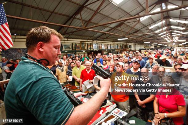 Eric Worstell holds up a Glock 19 9mm as he auctions off thousands of items seized from disgraced financier R. Allen Stanford's Houston offices, at...