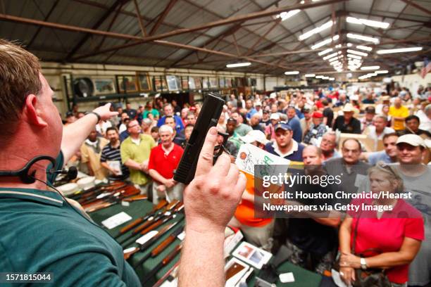 Eric Worstell holds up a Glock 19 9mm as he auctions off thousands of items seized from disgraced financier R. Allen Stanford's Houston offices, at...