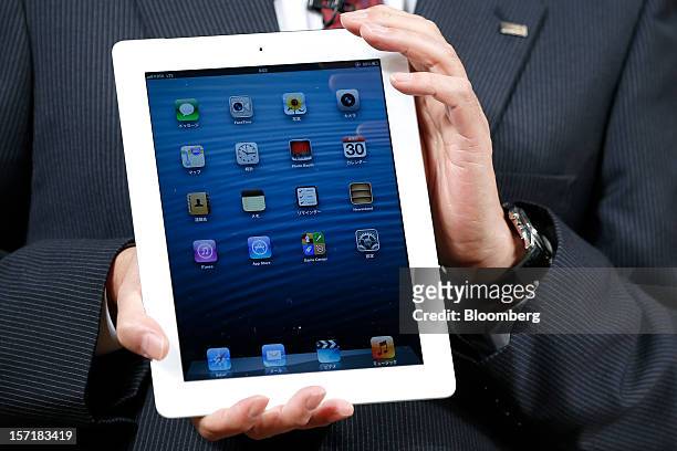 Takashi Tanaka, president of KDDI Corp., holds an Apple Inc. IPad during a launch event at a KDDI store in Tokyo, Japan, on Friday, Nov. 30, 2012....