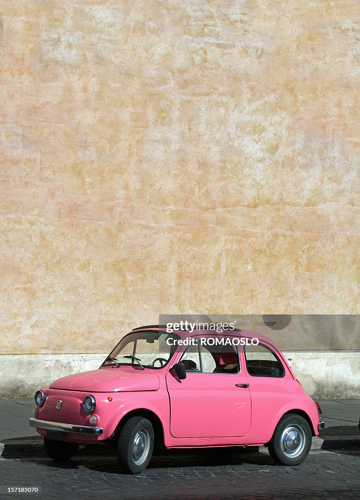 Small pink vintage Fiat car in Rome, Italy