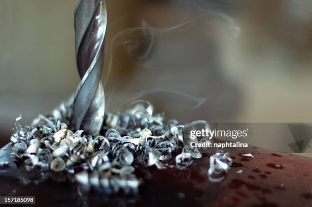 a silver drill turning with metal shavings and smoke - metal shavings stock pictures, royalty-free photos & images