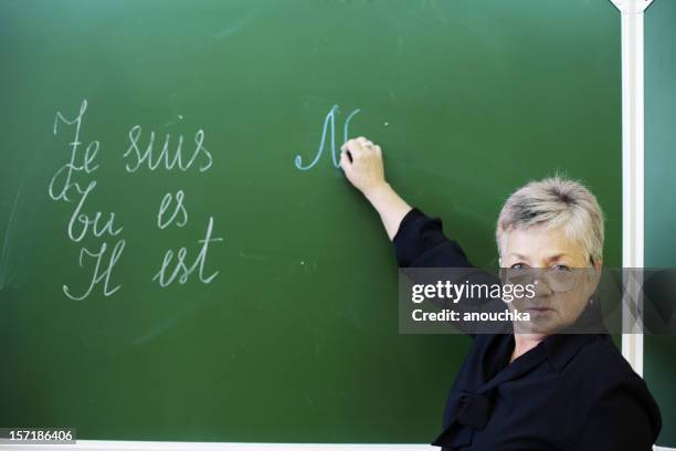 female teacher standing by blackboard, looking at camera - french language stock pictures, royalty-free photos & images