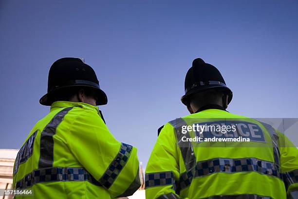 two british policemen wearing traditional helmets-click below for more. - police hat stock pictures, royalty-free photos & images