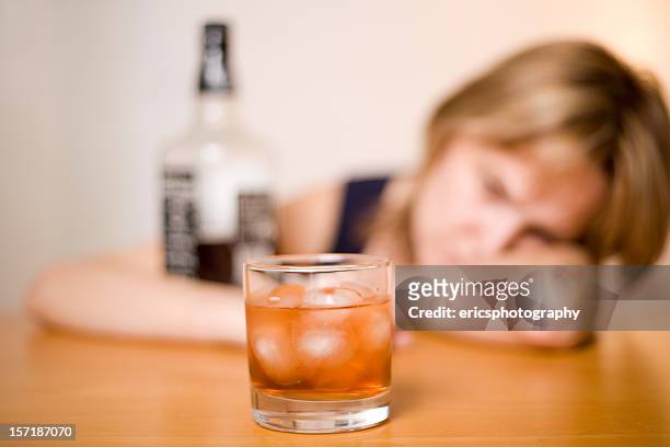 in focus glass of alcohol with blurry woman in background - alcohol abuse stock pictures, royalty-free photos & images