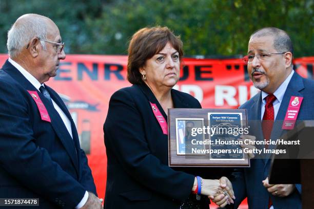 Mary Zapata clutches a plaque honoring her son, slain immigration agent Jaime Zapata, as she shakes hands with Thomas Hinojosa, Acting Special Agent...