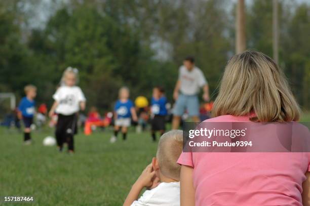 soccer mom and brother watching sister play game - young supporter stock pictures, royalty-free photos & images