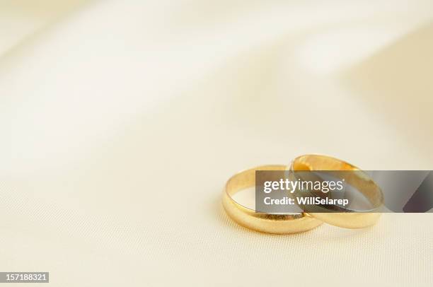 zwei ringe auf weißem seiden-hintergrund - wedding rings stock-fotos und bilder