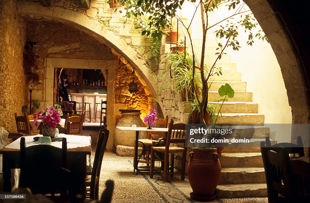 Romantic restaurant interior in Greece, wooden tables, chairs, stone stairs