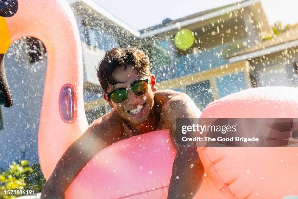 cheerful young man floating on raft in pool - poolparty stockfoto's en -beelden