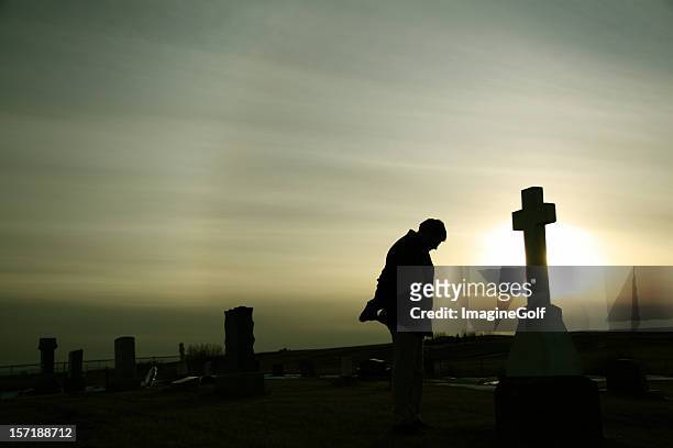 silhouette of caucasian man mourning at graveyard - mourner stock pictures, royalty-free photos & images