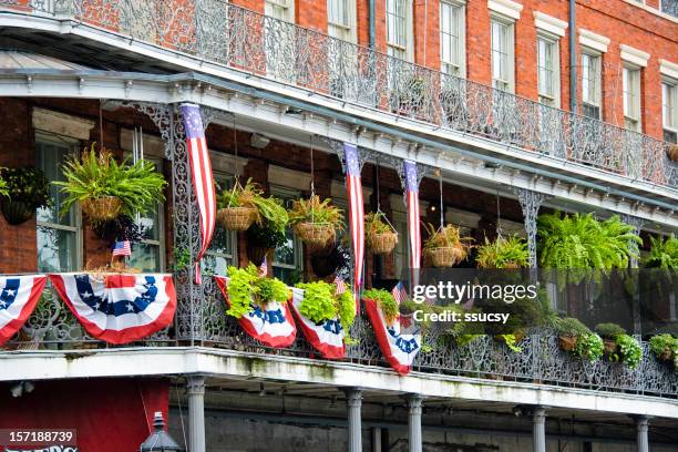 new orleans balcony, wrought iron railing, flag banners, french quarter - new orleans parade stock pictures, royalty-free photos & images