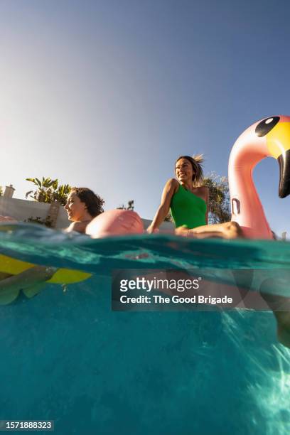 female friends floating on rafts in swimming pool - pool boat stock pictures, royalty-free photos & images