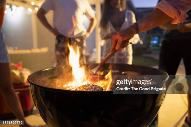 mid section of man cooking hamburgers on grill - fire brigade stock-fotos und bilder
