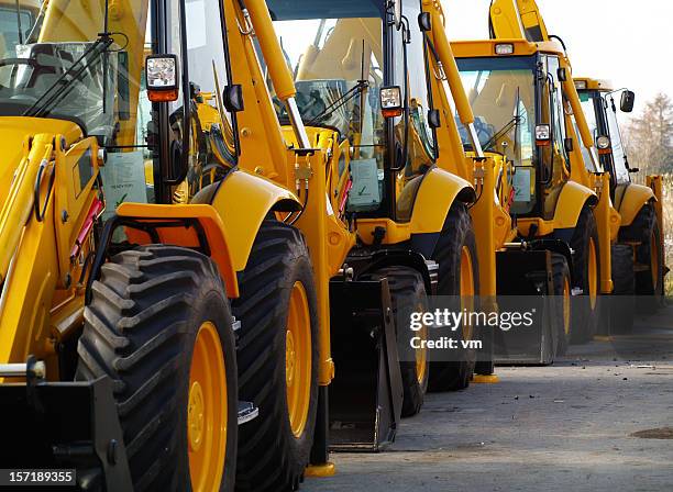 diggers in a row on industrial parking lot - graafmachine stockfoto's en -beelden