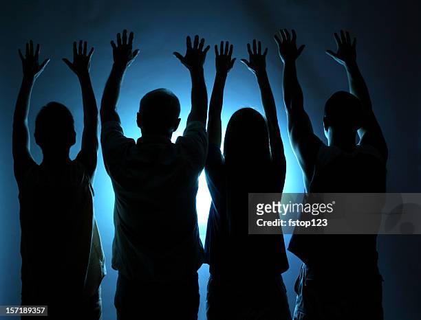 gruppo di persone silhouette. braccia alzate in lodi. luce blu. - religione foto e immagini stock