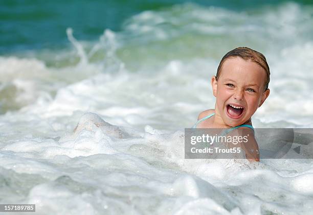 young girl playing in the waves at sea - wading-through-river stock pictures, royalty-free photos & images