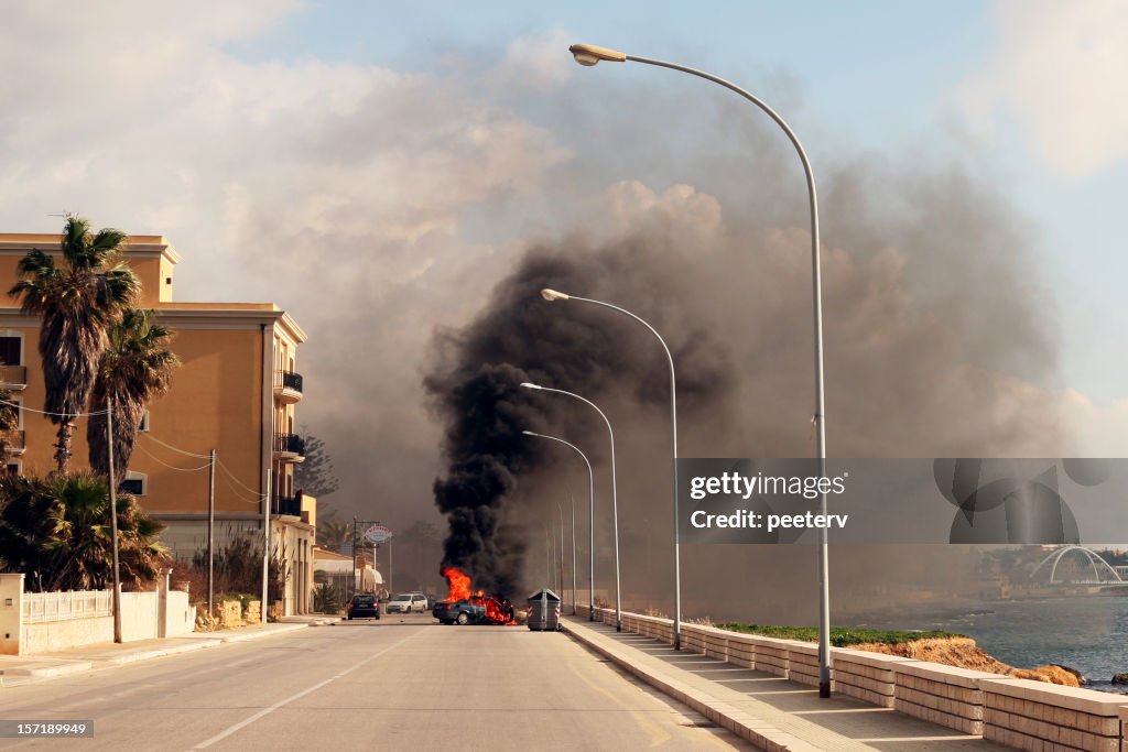Burning car in the street of sicilian town.