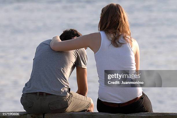 concerned woman comforts frustrated man at a beach - depression land feature stock pictures, royalty-free photos & images