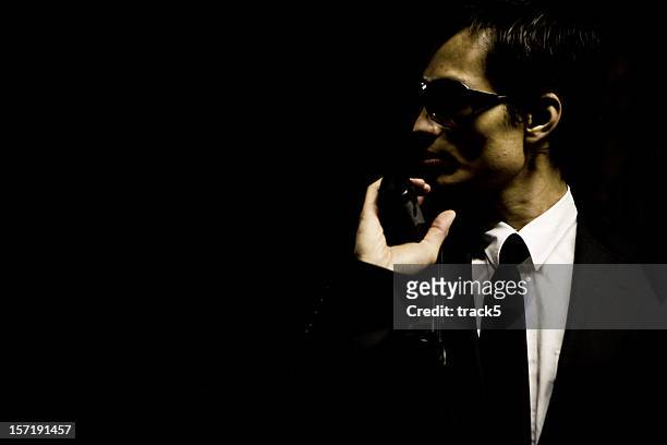 suited hitman with gun hiding in a darkened corner watching... - japanese mafia stock pictures, royalty-free photos & images