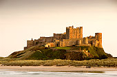 Bamburgh Castle daytime with people walking on beach