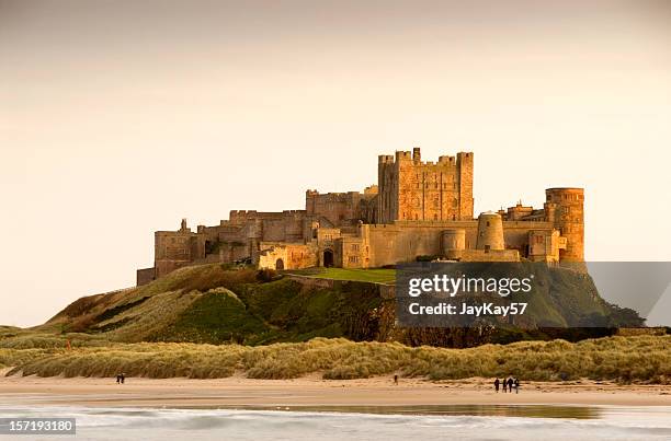 bamburgh castle daytime with people walking on beach - northumberland bildbanksfoton och bilder