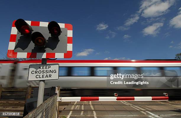 high speed train going pass a crossing - train barriers stock pictures, royalty-free photos & images