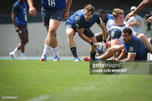 France's scrum-half Baptiste Serin passes the ball during a training session looks on during a training session, as part of France's national rugby...