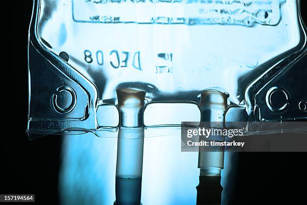 an iv drip in a dark room with a light behind it - iv fluid stock pictures, royalty-free photos & images