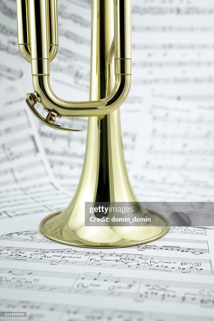 Close-up of golden trumpet standing on music notes, side view