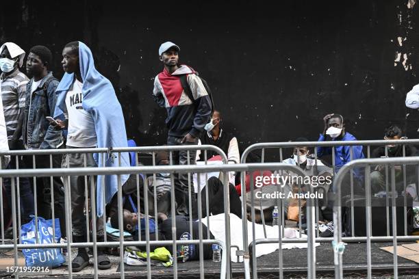 Migrants line up outside Roosevelt Hotel while waiting for placement inside a shelter as asylum seekers camp outside the hotel as the Manhattan...