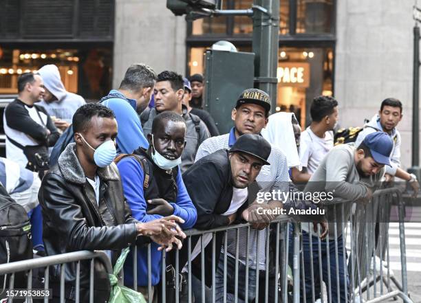 Migrants line up outside Roosevelt Hotel while waiting for placement inside a shelter as asylum seekers camp outside the hotel as the Manhattan...