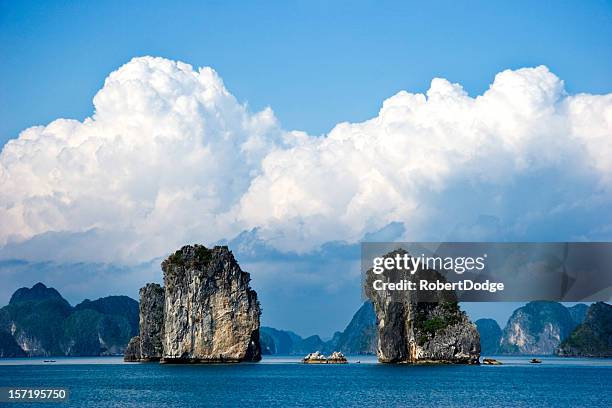 two large rock structures in halong bay under fluffy clouds - halong bay vietnam stock pictures, royalty-free photos & images