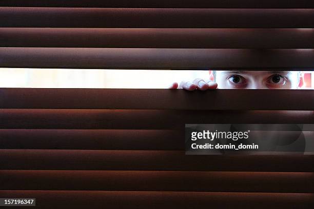 uomo sta guardando attraverso il foro nella finestra persiane in legno di - bad neighbor foto e immagini stock