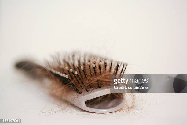 hairbrush with strands of auburn hair stuck in it - hair loss stock pictures, royalty-free photos & images