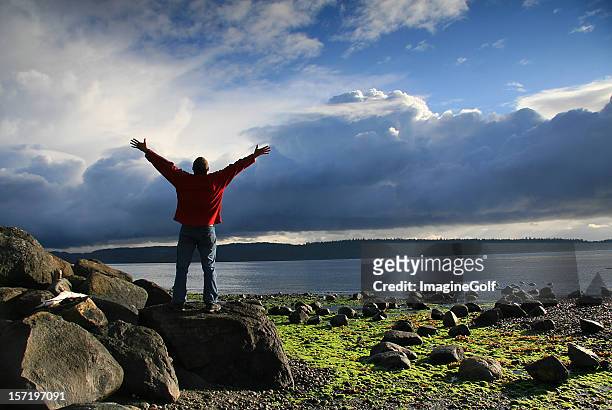man raising his hands to heaven in beautiful ocean setting - praising religion stock pictures, royalty-free photos & images