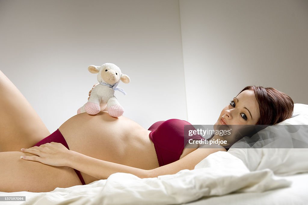 Pregnant teenager with fluffy animal in bed