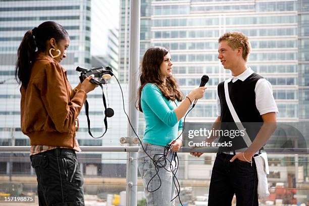 a young male teenager being interviewed by two young females - media interview stockfoto's en -beelden