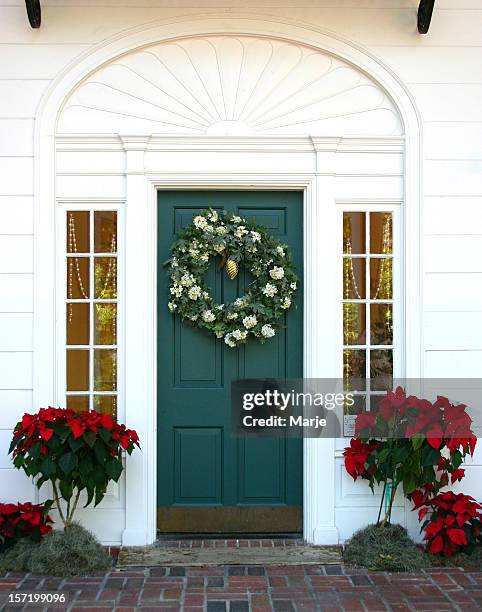 green door to a white house with a christmas wreath on it - holiday wreath stockfoto's en -beelden