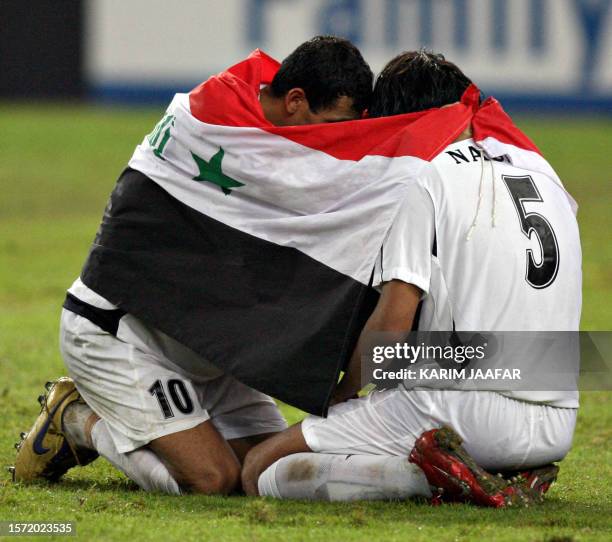 Iraq's Younis Mahmoud and Nashat Akram are wrapped in the Iraqi flag after their team defeated South Korea during their semi-final match at the Bukit...