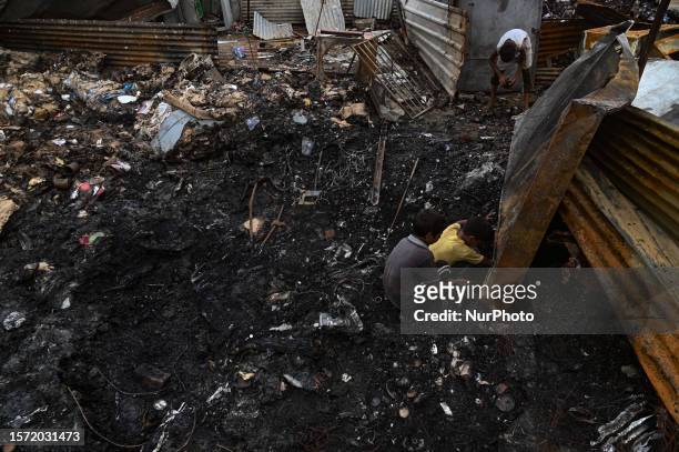 Boys search for scrap items in a burnt shop that was allegedly set on fire by a mob on Tuesday midnight following clashes between Hindus and Muslims...