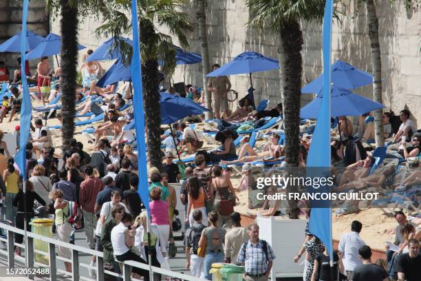 People walk on the banks of the river Seine, 21 July 2007 in Paris, on the first day of "Paris Plages", the ephemeral beach set up on the banks of...