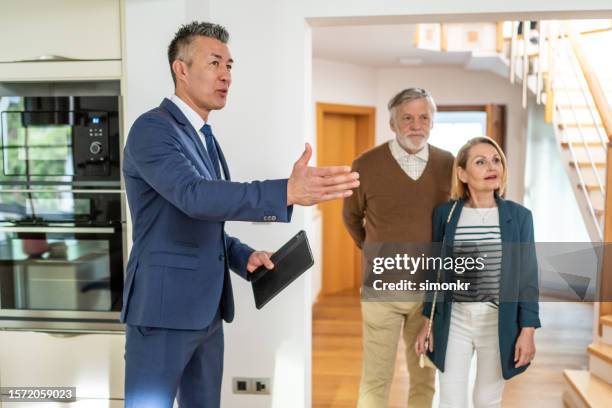 agente inmobiliario que muestra casa a pareja - visita de inmuebles en venta fotografías e imágenes de stock