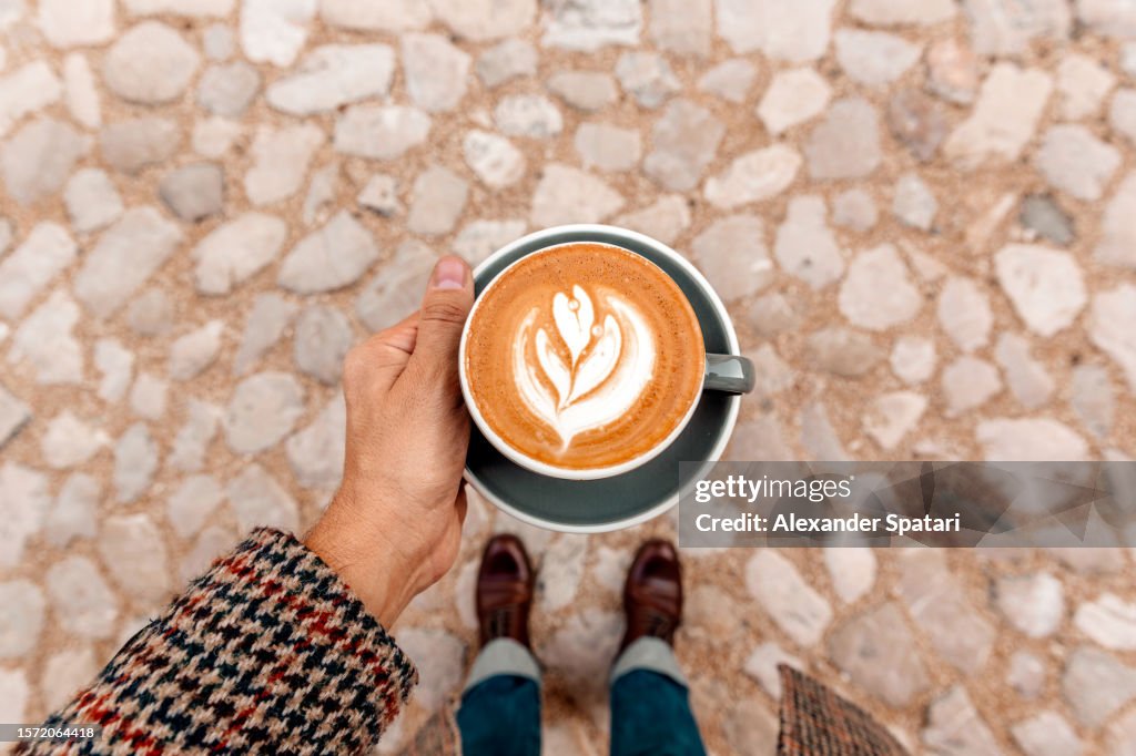 Man drinking coffee outdoors, personal perspective high angle view
