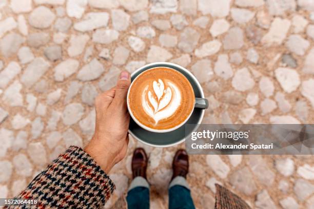 man drinking coffee outdoors, personal perspective high angle view - bebida caliente fotografías e imágenes de stock
