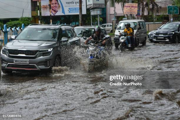 Commuters and office goers are seen making their way through a flooded road in Kolkata , India , on 2 August 2023 . Overnight rain caused many parts...