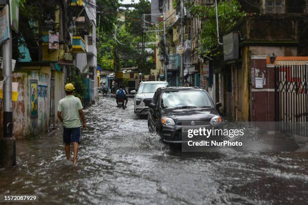 Commuters and office goers are seen making their way through a flooded road in Kolkata , India , on 2 August 2023 . Overnight rain caused many parts...